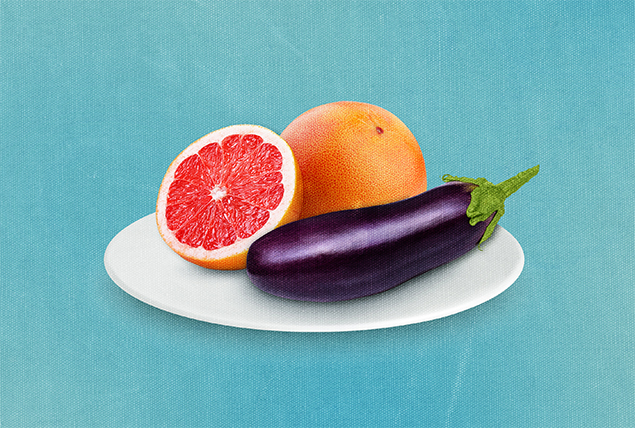 An eggplant sits next to halved grapefruit on a plate against a teal background.