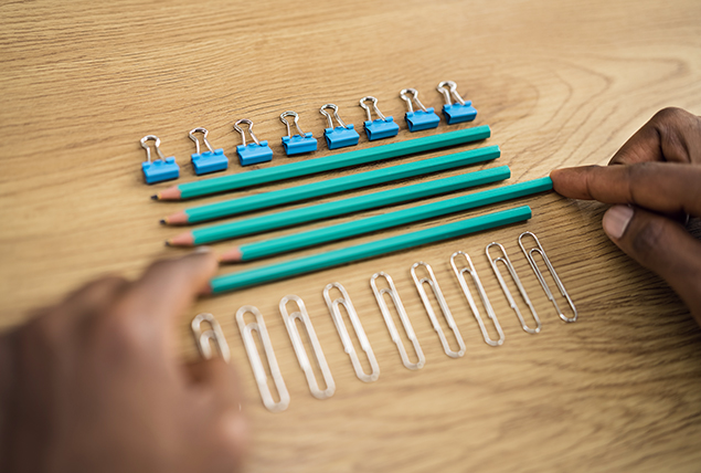 A pencil is being slid into a straight line of other pencils in between a row of paperclips and a row of binder clips.