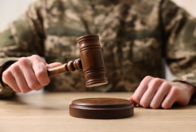 A uniformed military person is holding a gavel.