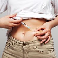 A person injecting bottom growth testosterone into their abdomen. 