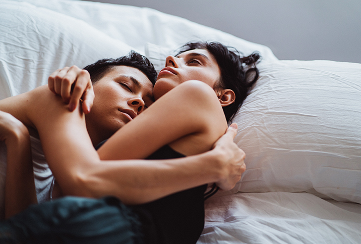 two people hold each other and cuddle in white bed