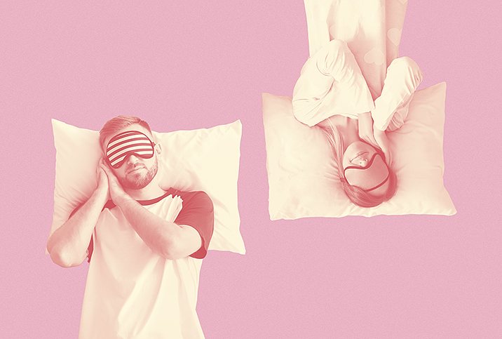 A man and woman sleep in opposite directions against a pink background.