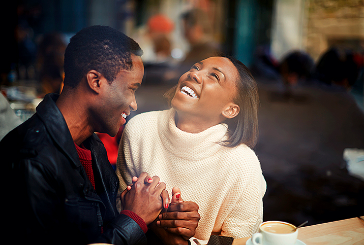 man and woman sit at restaurant bar and alugh together 