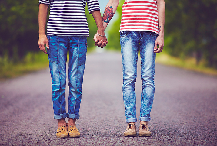 Two people hold hands while standing in the middle of the street.