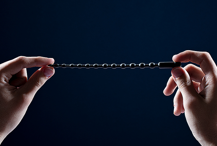 Two hands holding up a black sounding rod.