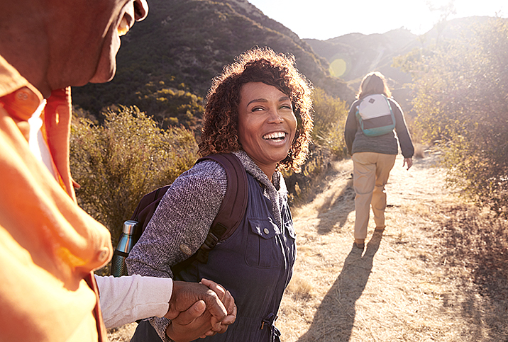 woman smiles at friend while on hike with sun shining