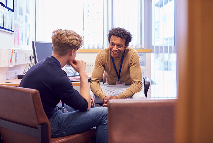 A PrEP counselor smiles as he talks with a young man in his office.