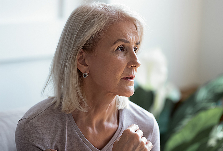 woman looks stressed and holds her hand to her chest