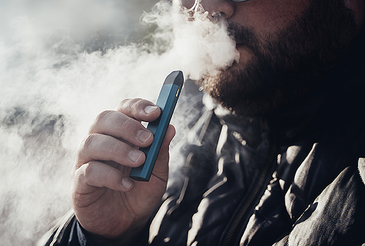 A man blows out smoke after using an e-cigarette.