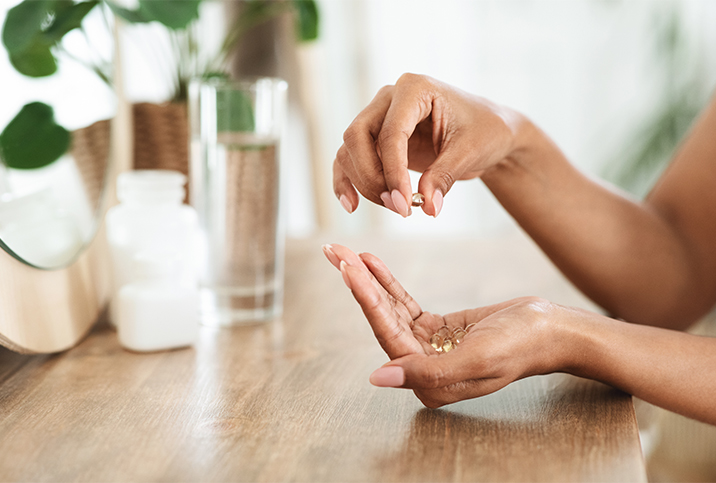A woman's hands holding vitamins that help with vaginal dryness.