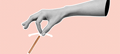An IUD coil is held between two fingers.