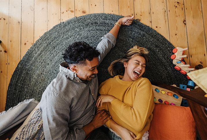 A-couple-laughs-while-laying-together-on-floor