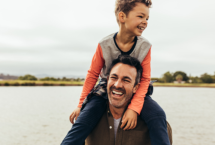 A-child-sits-on-hist-dads-shoulders-and-both-laugh