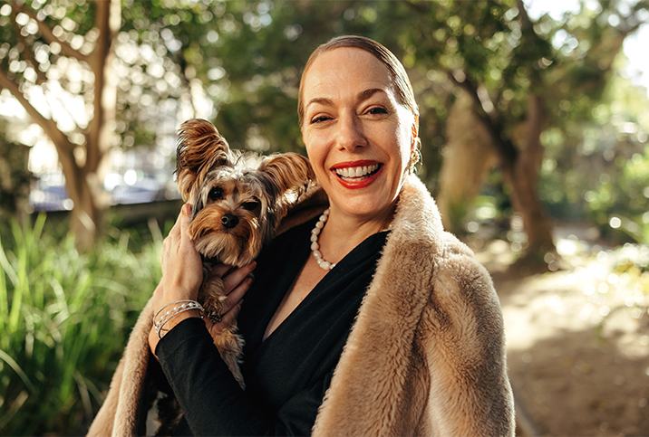 A single woman smiles holding her dog.