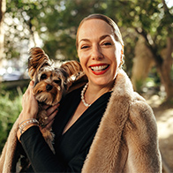 A single woman smiles holding her dog.