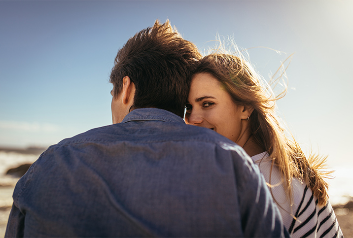 A couple sits with their backs to the camera and one of them looks back over her shoulder.