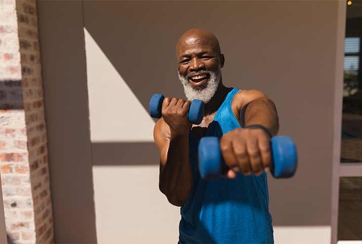 A man in workout gear exercises with weights in his hands.