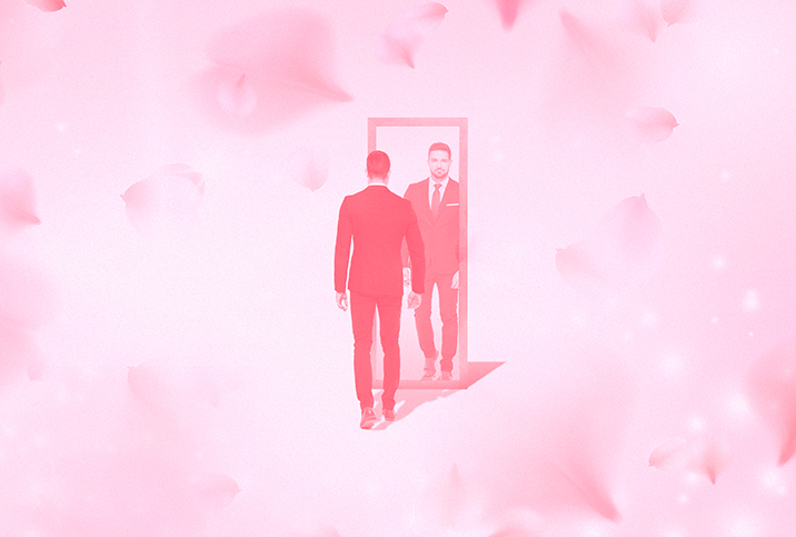 A man stands in front of a mirror with a pink cloudy background.