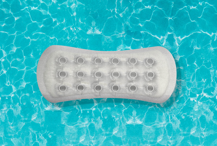 A pool floaty shaped like a menstrual pad, floats in a blue pool.