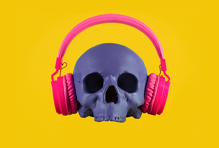 A purple skull wearing pink headphones sits on a bright yellow background.