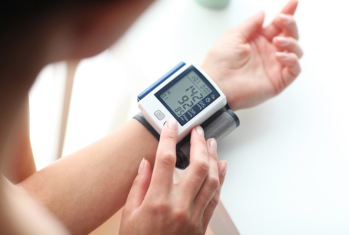 A pregnant woman uses a self-monitoring blood pressure gadget.