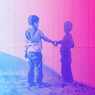 A little boy reaches out to touch his shadow on a pink wall. 