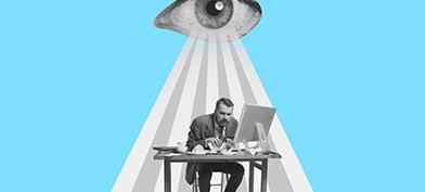 An eye beams down on a stressed man working at his desk.