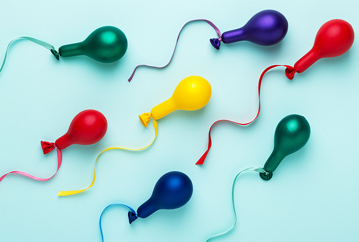 Multiple colors of barely blown up balloons have a string tied on the end to look like sperm.