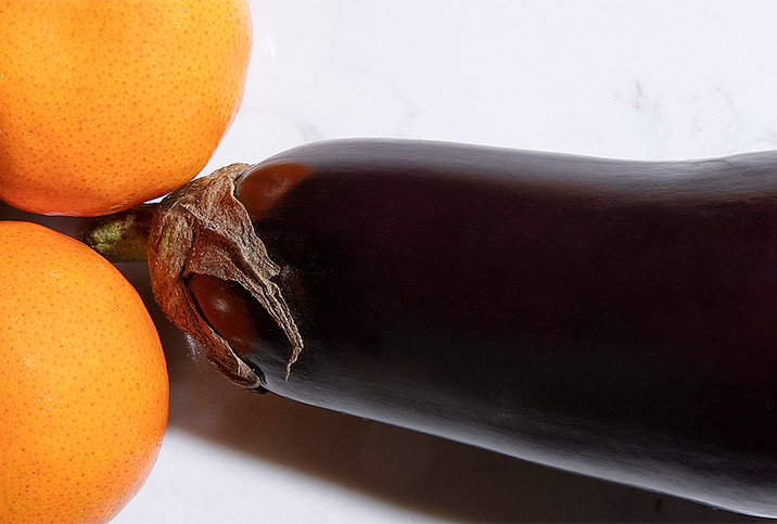 An eggplant is placed adjacent to two oranges like penis and testicles.