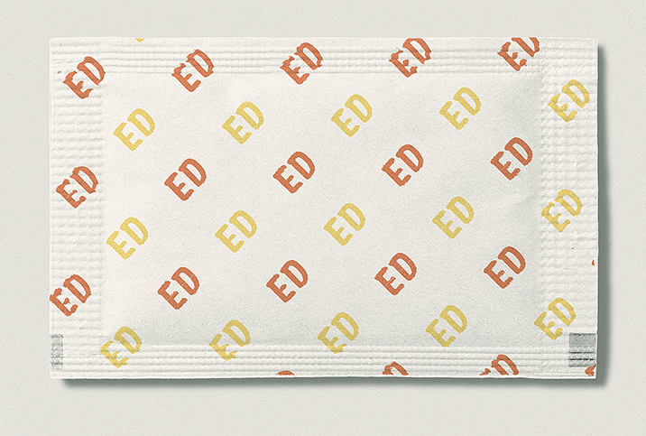 A sugar packet has ED written in yellow and orange repeatedly in a pattern.