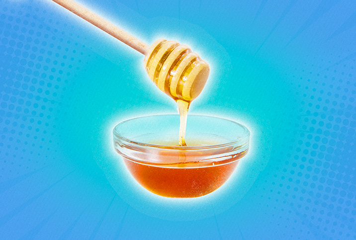 Honey is falling down from a dipper into a small dish against a blue background.