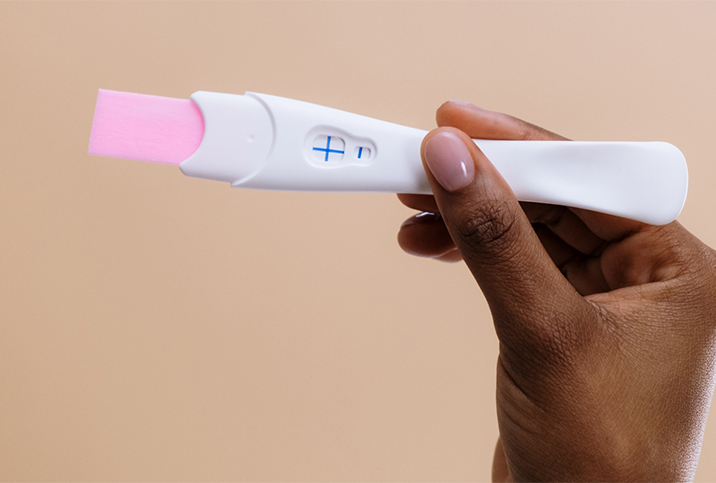 A hand holds a pregnancy test.