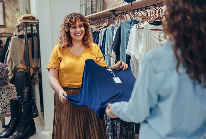 A sales associate shows clothing to a woman. 