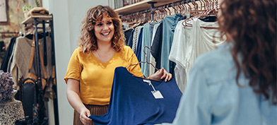 A sales associate shows clothing to a woman. 