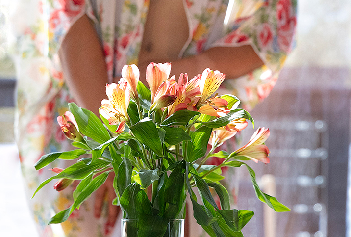 A bunch of flowers are centered in the frame with a blurred woman holding them in the background.