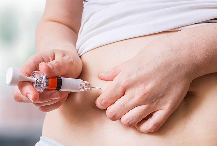 A woman injects fertility hormones inter her hip with a needle.