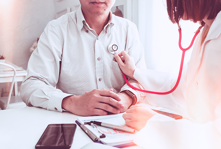 A doctor listens to the heart of a man with her stethoscope.