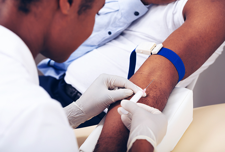 A gloved nurse inserts a needle into a patient's arm.