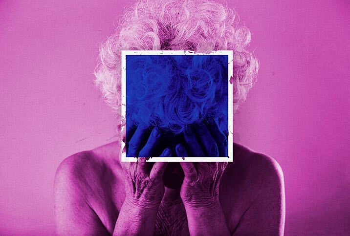 An elderly person with a pink filter holds their head in their hands and a blue, transparent square covers their face.