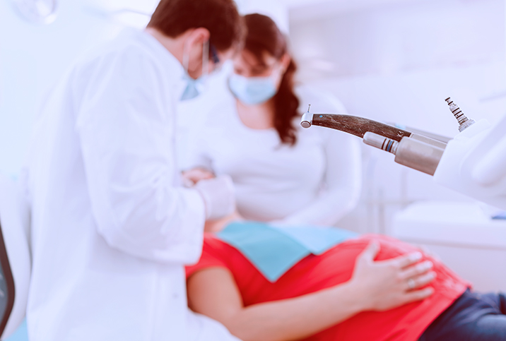 A pregnant woman is having her teeth examined at the dentist.
