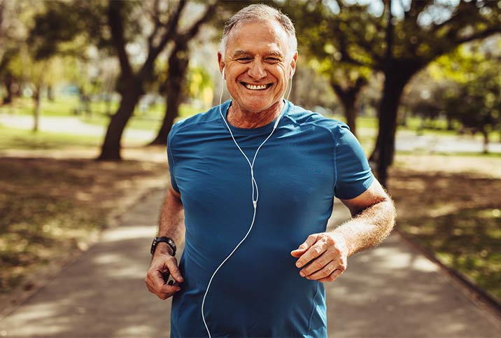 A man smiles while jogging and listening to music.