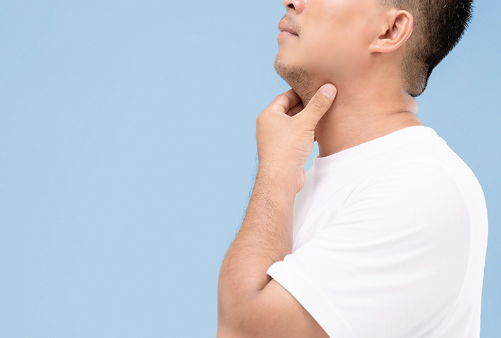 A man holds his hand along his throat to check his glands.