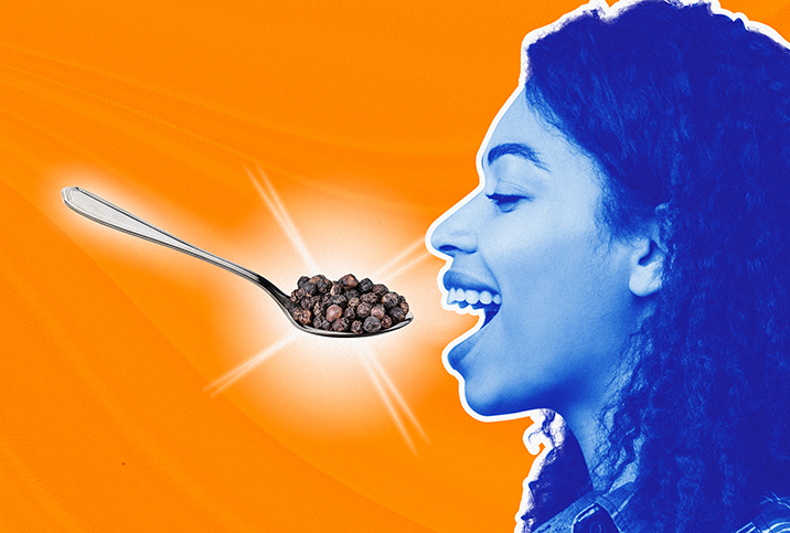 A blue woman opens her mouth for a spoon full of pepper corns.