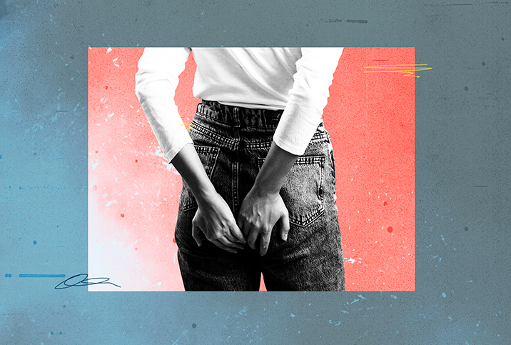 A woman in jeans holds on to her butt as she feels pain during her period.