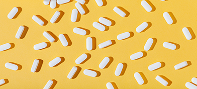 White zinc pills are spread out against a white surface with a pill bottle in the corner.