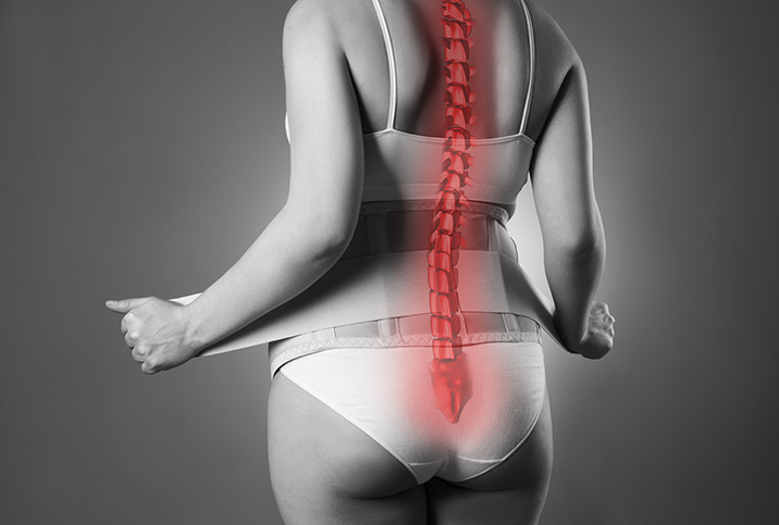 The back of a pregnant woman is shown in black and white with her spine glowing red.