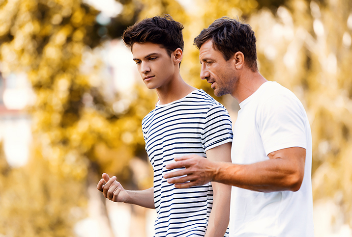 A father walks with his son having a discussion about consent.