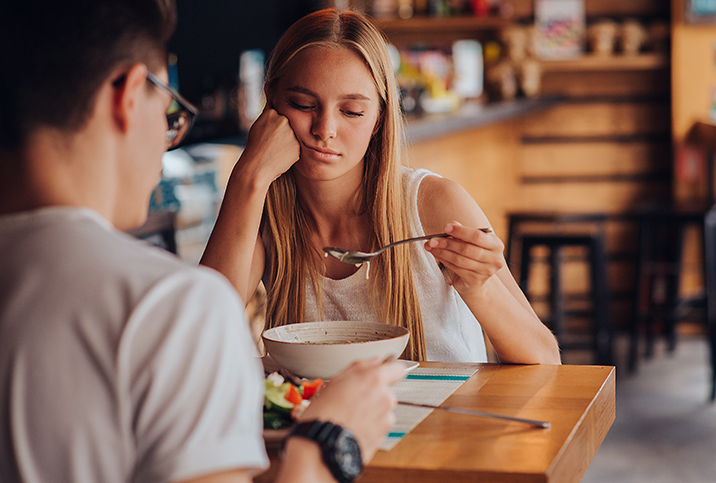 A woman looks negatively at her food while on a date.