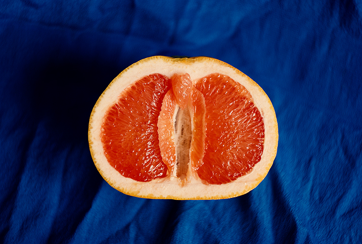 Half of a grapefruit sits open-faced against a blue cloth.
