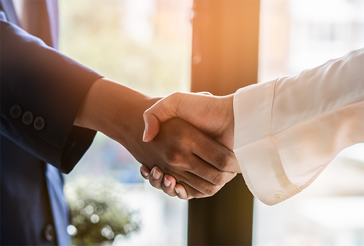 A person with a blue sleeve is shaking hands with someone with a white sleeve.